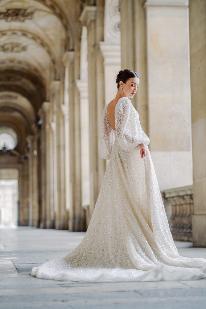 Paris pre-wedding session at the Louvre with bride in a sequined gown with a full train, long sleeved, deep plunging neckline and back, photographed by Italy destination photographer